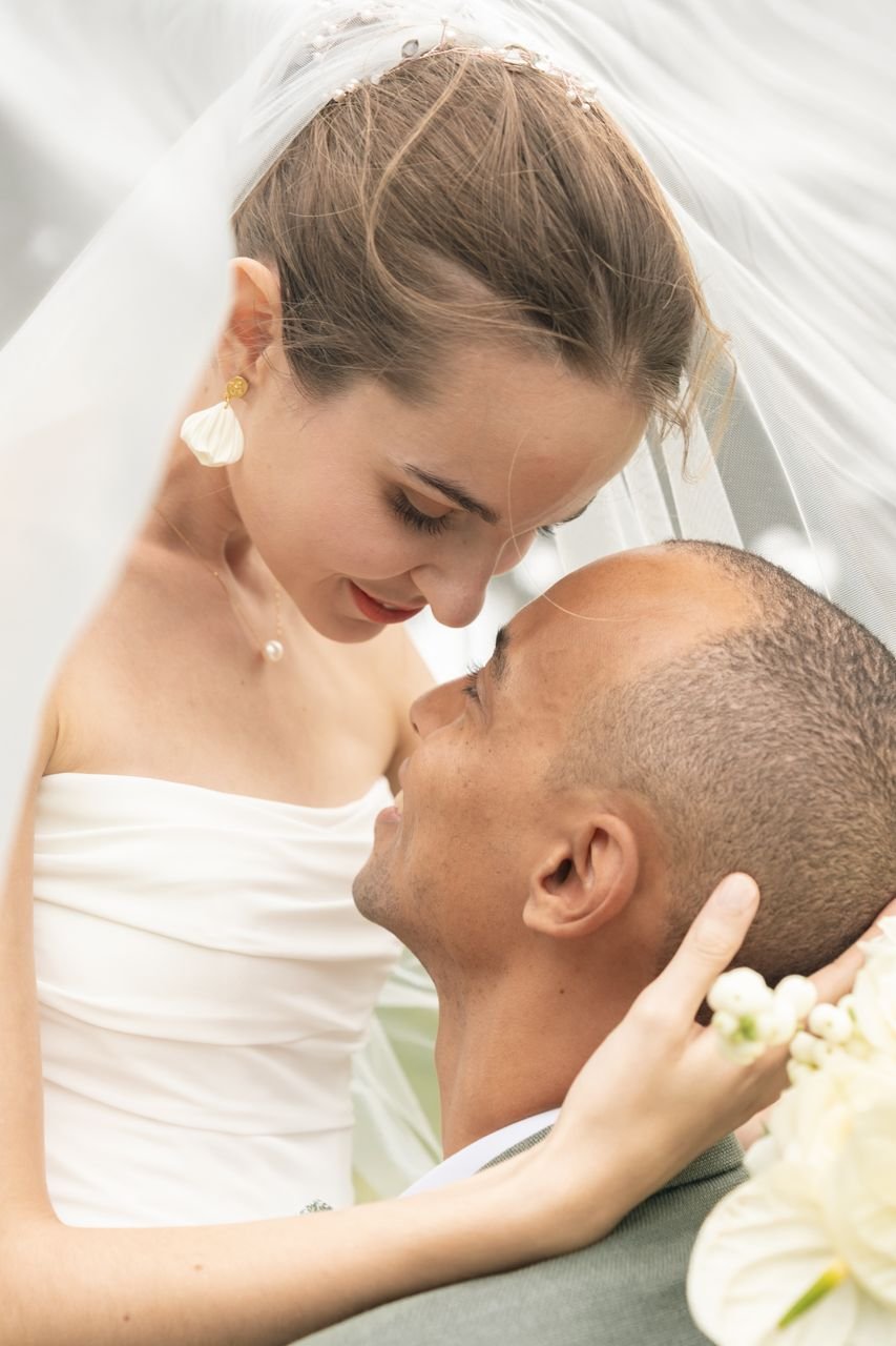 Les mariés échangent un regard sous le voile, leurs visages rapprochés