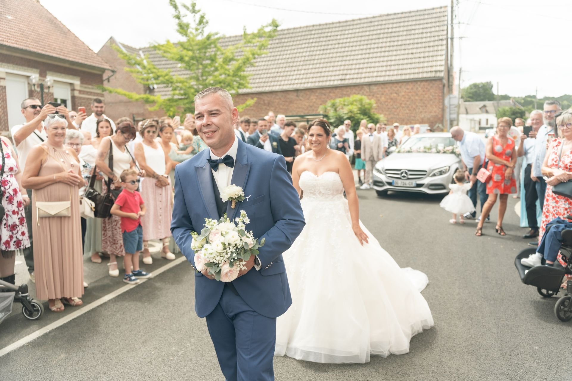 Les mariés avancent devant leurs invités, le marié tenant le bouquet