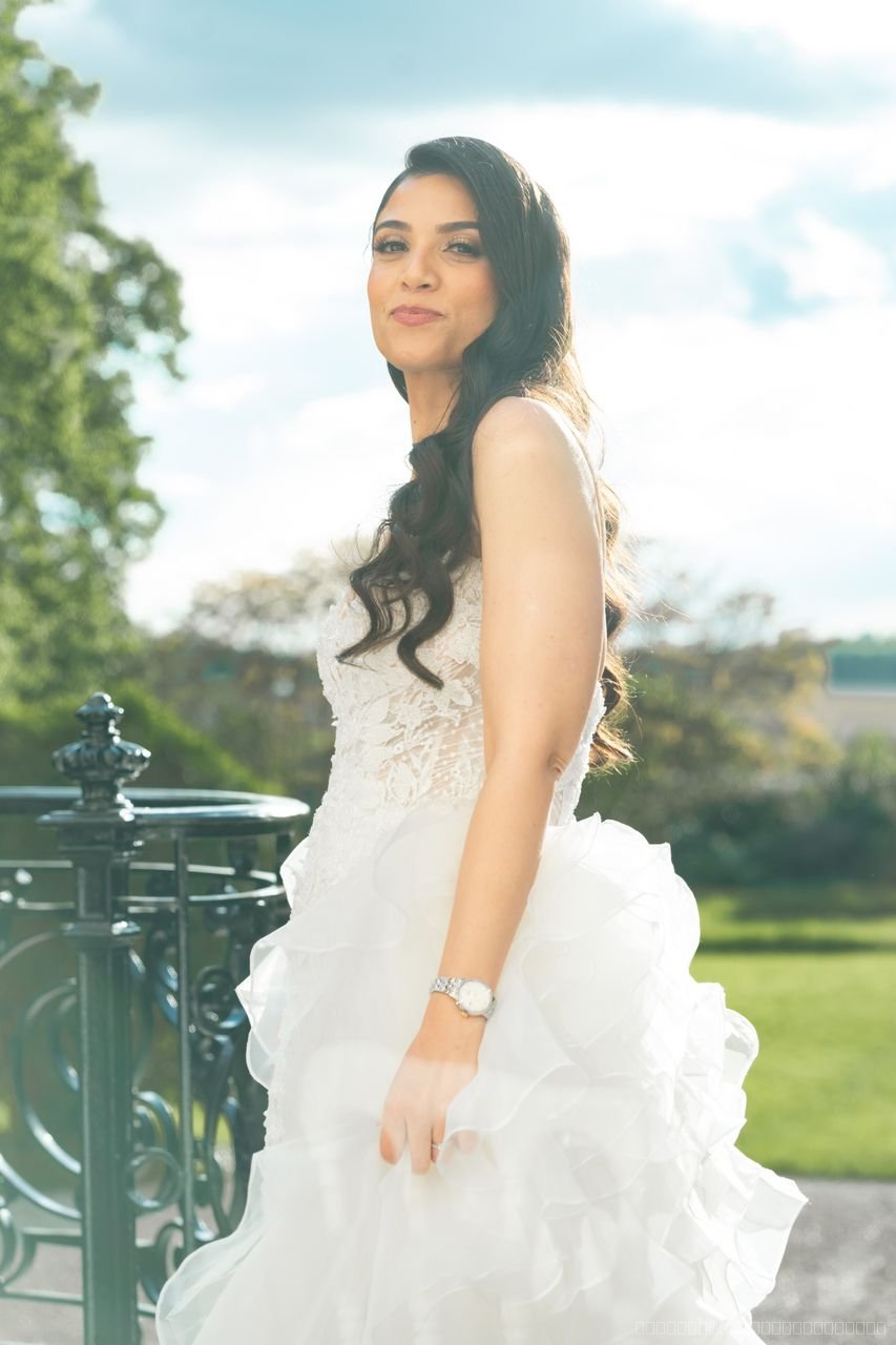 Portrait de la mariée en robe à volants près d’une balustrade, en extérieur
