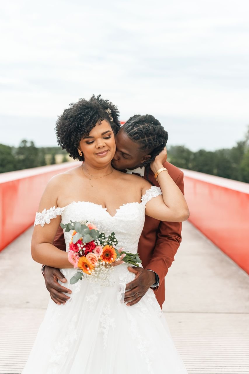 Le couple s’enlace sur un pont rouge, la mariée tenant son bouquet