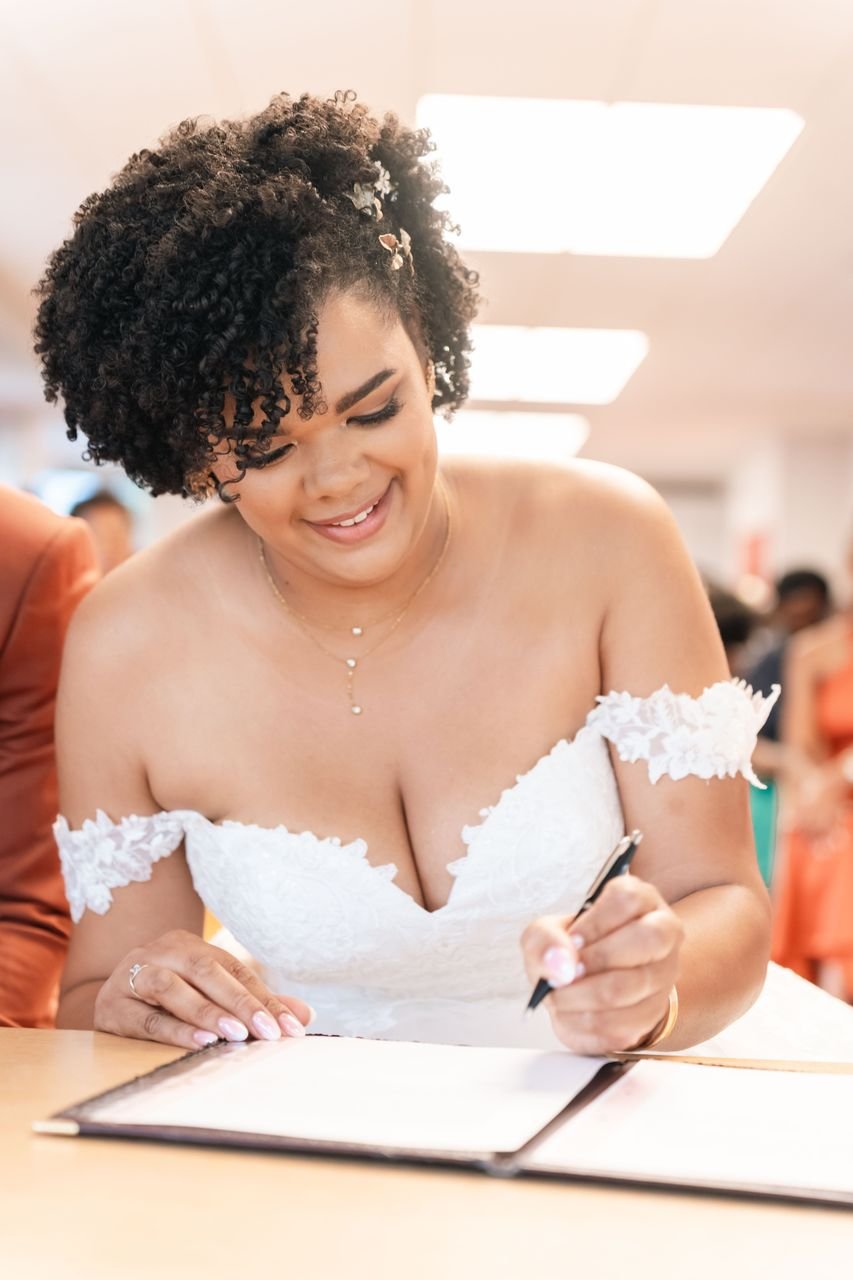La mariée souriante signe un registre pendant la cérémonie