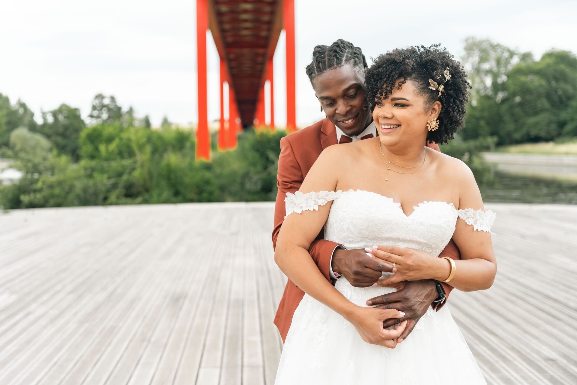 Le couple sourit en s’enlaçant devant la structure d’un pont rouge