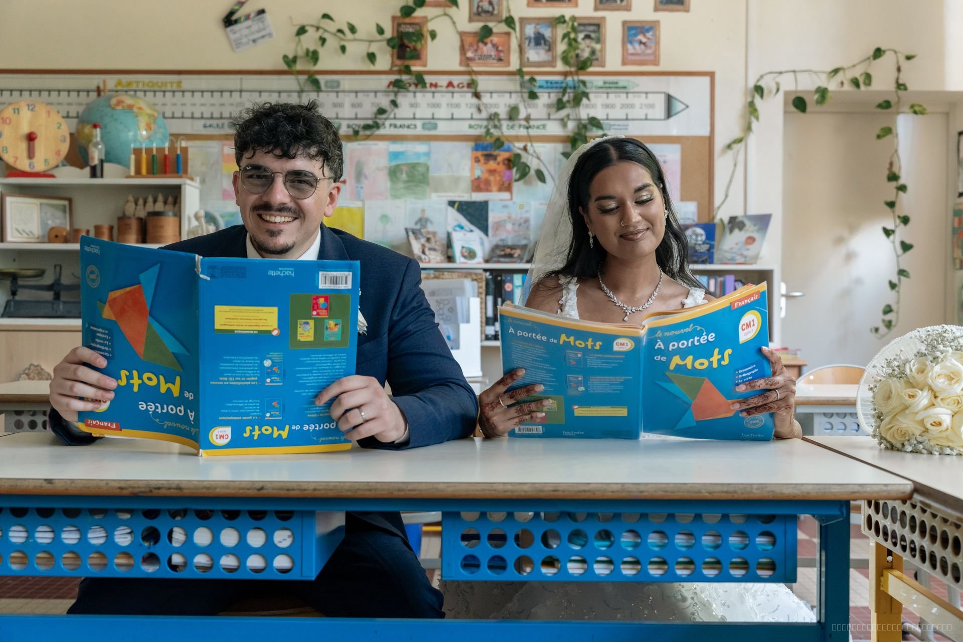 Les mariés assis à un bureau de classe feuillettent des livres pour enfants