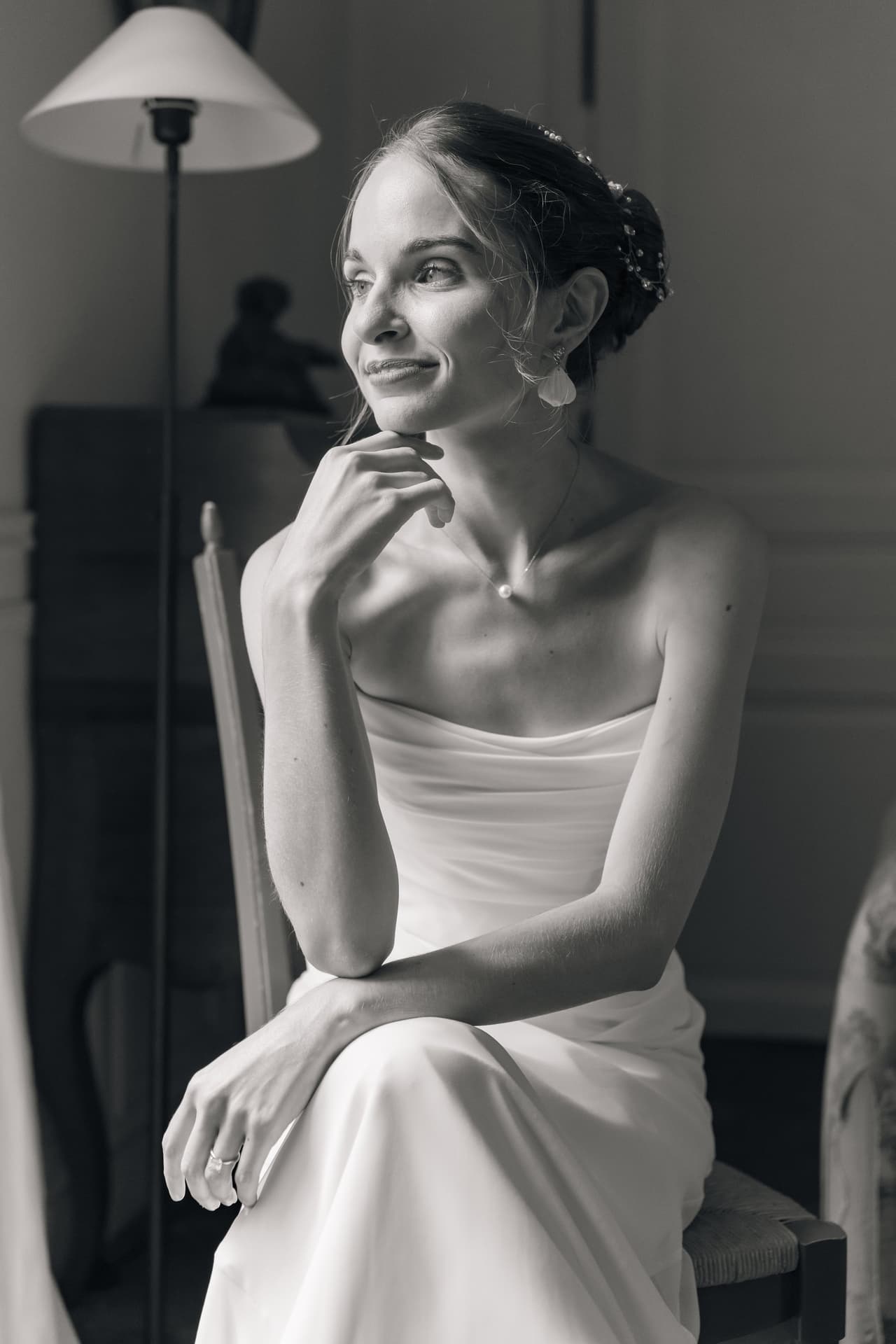Portrait en noir et blanc de la mariée assise, le visage tourné vers la lumière
